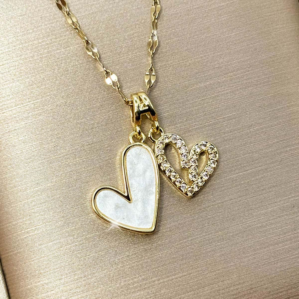 Damen Halskette mit zwei Herz-Anhängern, ein Herz in edler Perlmutt-Optik und ein Herz im Cut-Out-Design mit glitzerndem Zirkonia Besatz, Nahaufnahme von links.