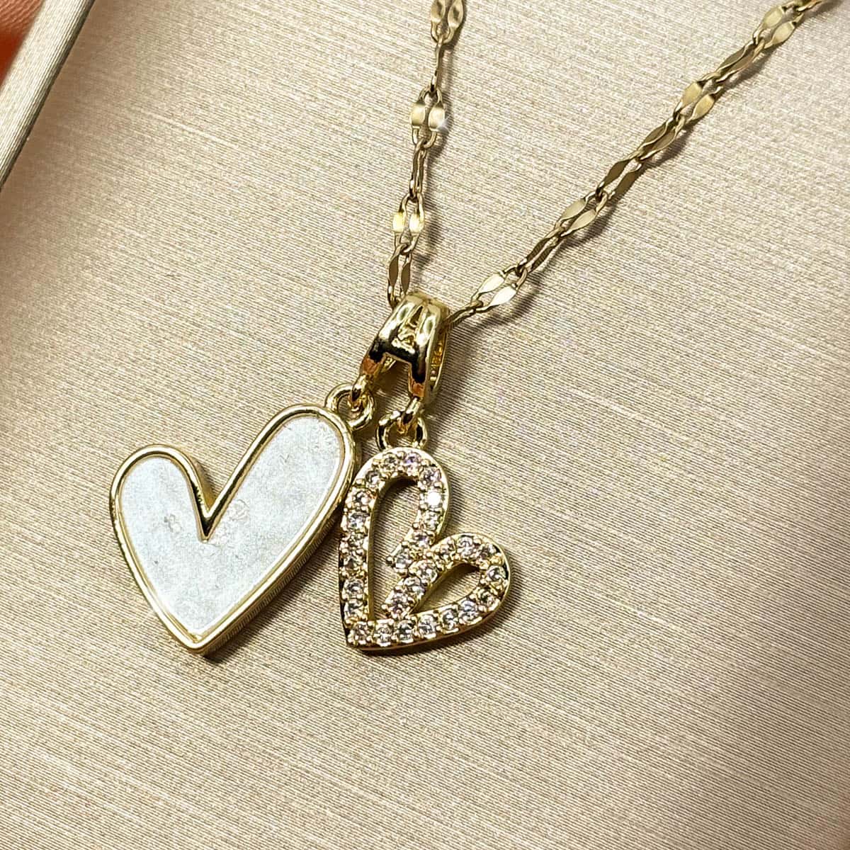 Damen Halskette mit zwei Herz-Anhängern, ein Herz in edler Perlmutt-Optik und ein Herz im Cut-Out-Design mit glitzerndem Zirkonia Besatz, Nahaufnahme von rechts.