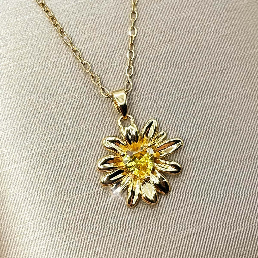 Halskette mit detailreichem Sonnenblumen-Anhänger und einem leuchtend gelben Zirkonia-Stein im Zentrum, Studio-Produktfoto von links.