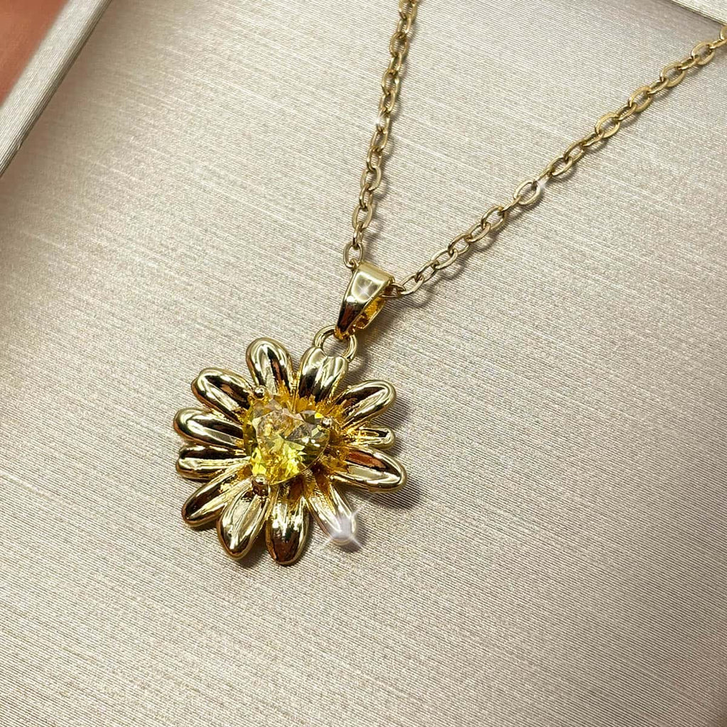 Halskette mit detailreichem Sonnenblumen-Anhänger und einem leuchtend gelben Zirkonia-Stein im Zentrum, Studio-Produktfoto von rechts.