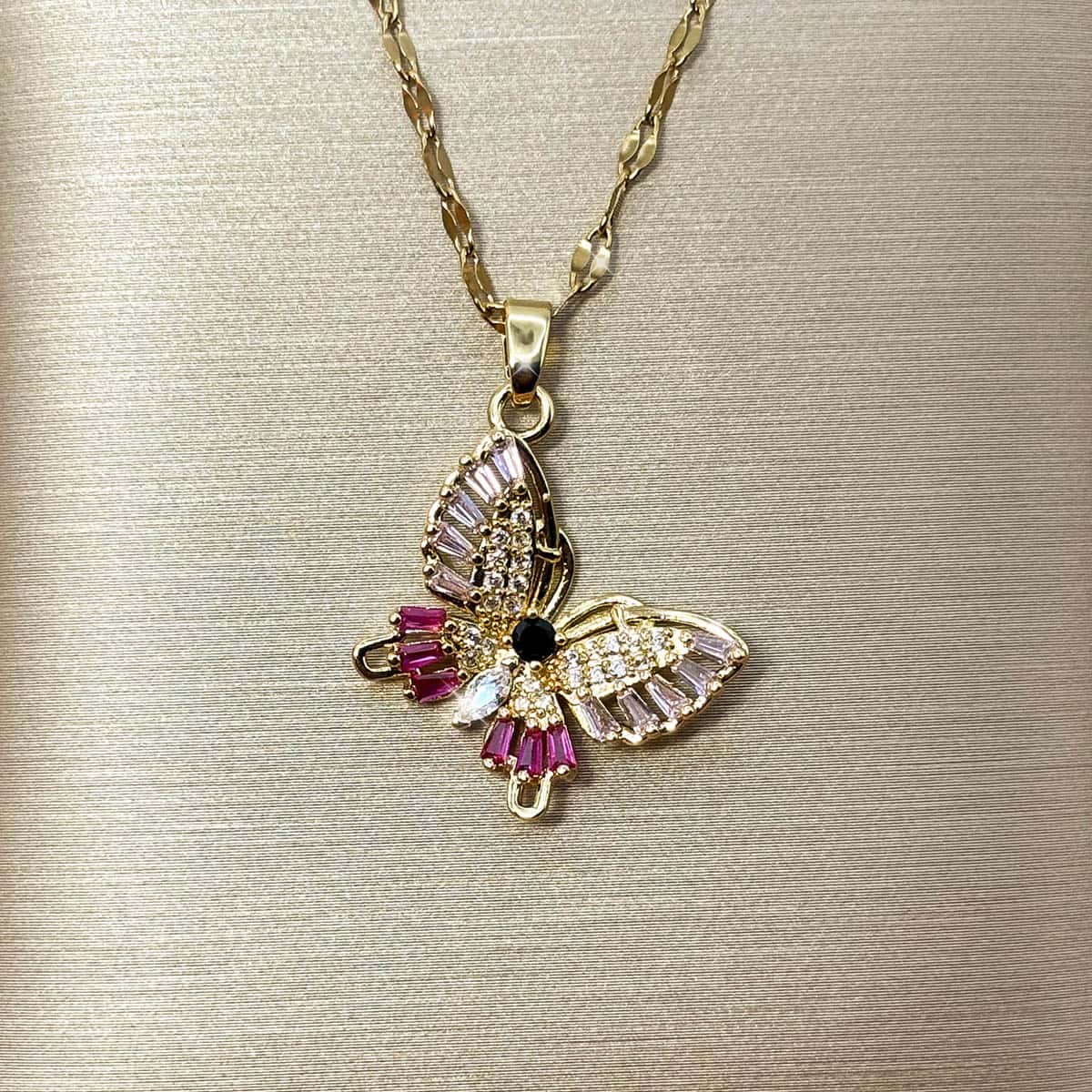 Halskette mit detailreichem Schmetterlings-Anhänger, verziert mit pinken, rosa und klaren Zirkonia-Steinen, Vorderansicht.