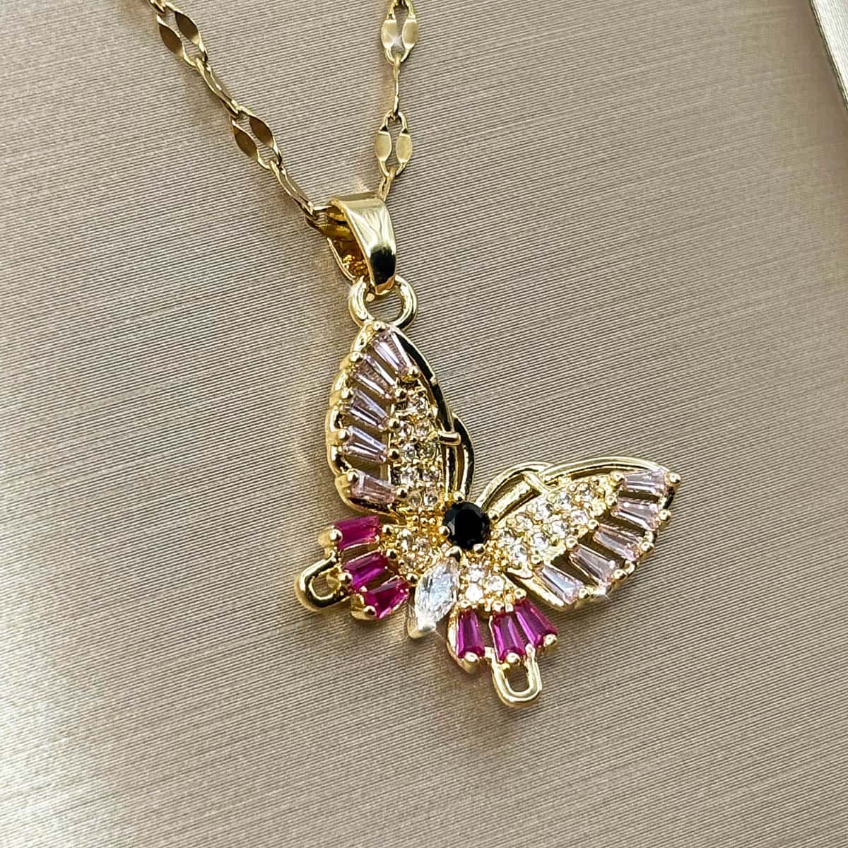 Halskette mit detailreichem Schmetterlings-Anhänger, verziert mit pinken, rosa und klaren Zirkonia-Steinen, Ansicht von links.