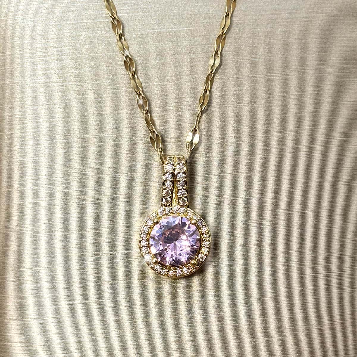 Halskette mit kreisrundem Anhänger, einem großen rosa Zirkonia-Stein im Zentrum und kleiner Zirkonia-Umrandung, Nahaufnahme