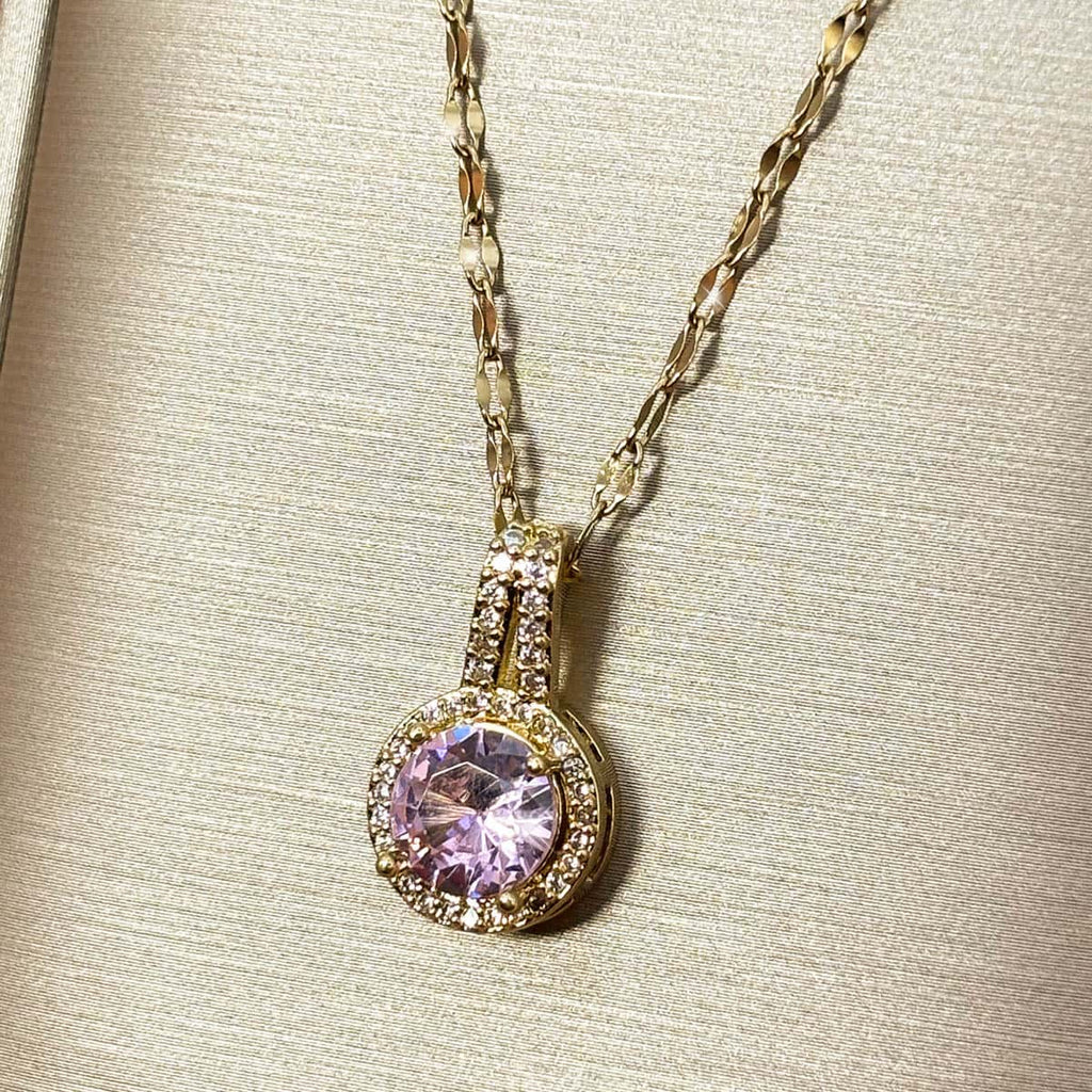 Halskette mit kreisrundem Anhänger, einem großen rosa Zirkonia-Stein im Zentrum und kleiner Zirkonia-Umrandung, Nahaufnahme von rechts.