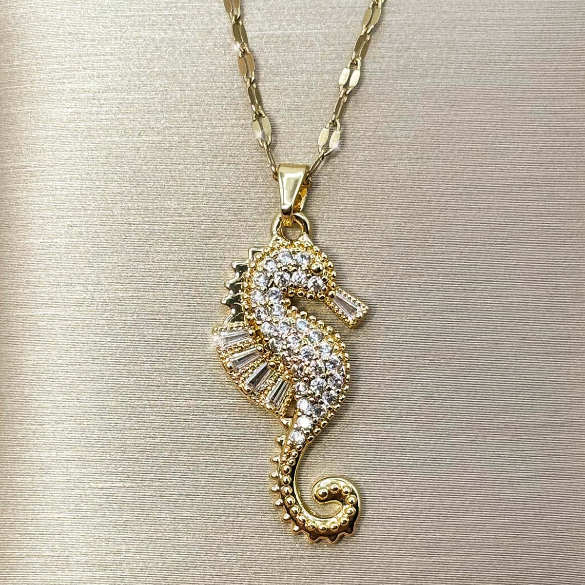 Goldene Damen Kette mit detailreichem Seepferdchen-Anhänger, besetzt mit weißen Zirkonia-Kristallen, Vorderansicht.