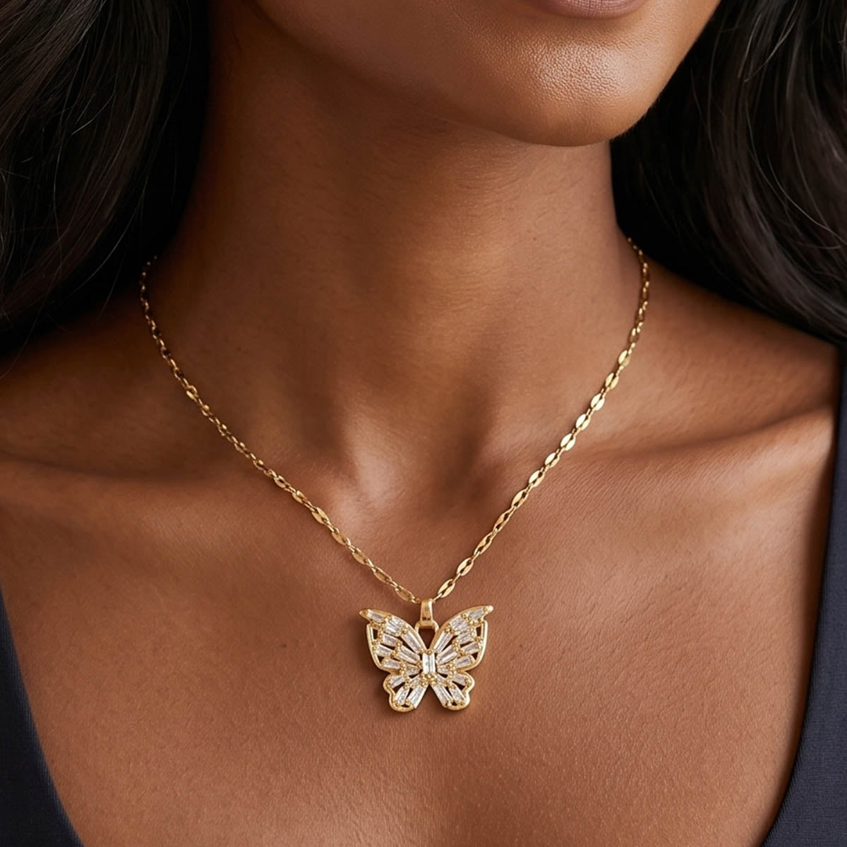 Damen Goldene Edelstahl Halskette mit einem funkelndem Schmetterling Anhänger am Hals eines Models getragen.