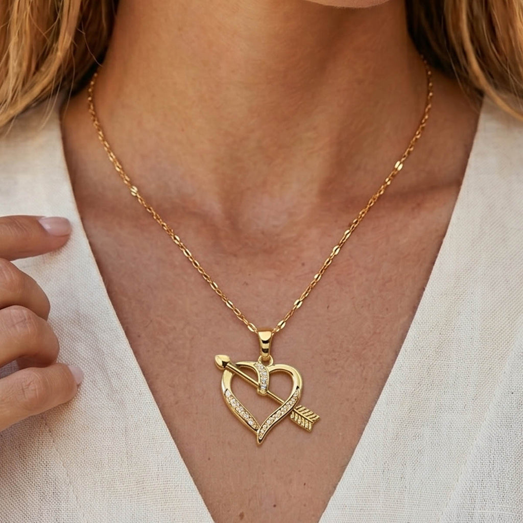 Goldene Edelstahl Halskette mit einem Herz Amor Pfeil Anhänger am Hals eines Models getragen.