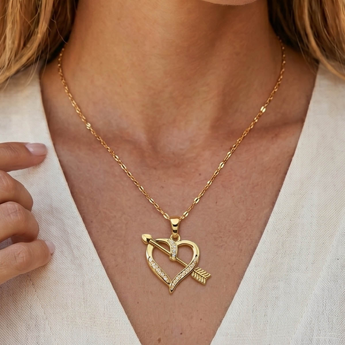 Goldene Edelstahl Halskette mit einem Herz Amor Pfeil Anhänger am Hals eines Models getragen.