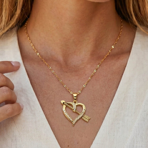 Goldene Edelstahl Halskette mit einem Herz Amor Pfeil Anhänger am Hals eines Models getragen.