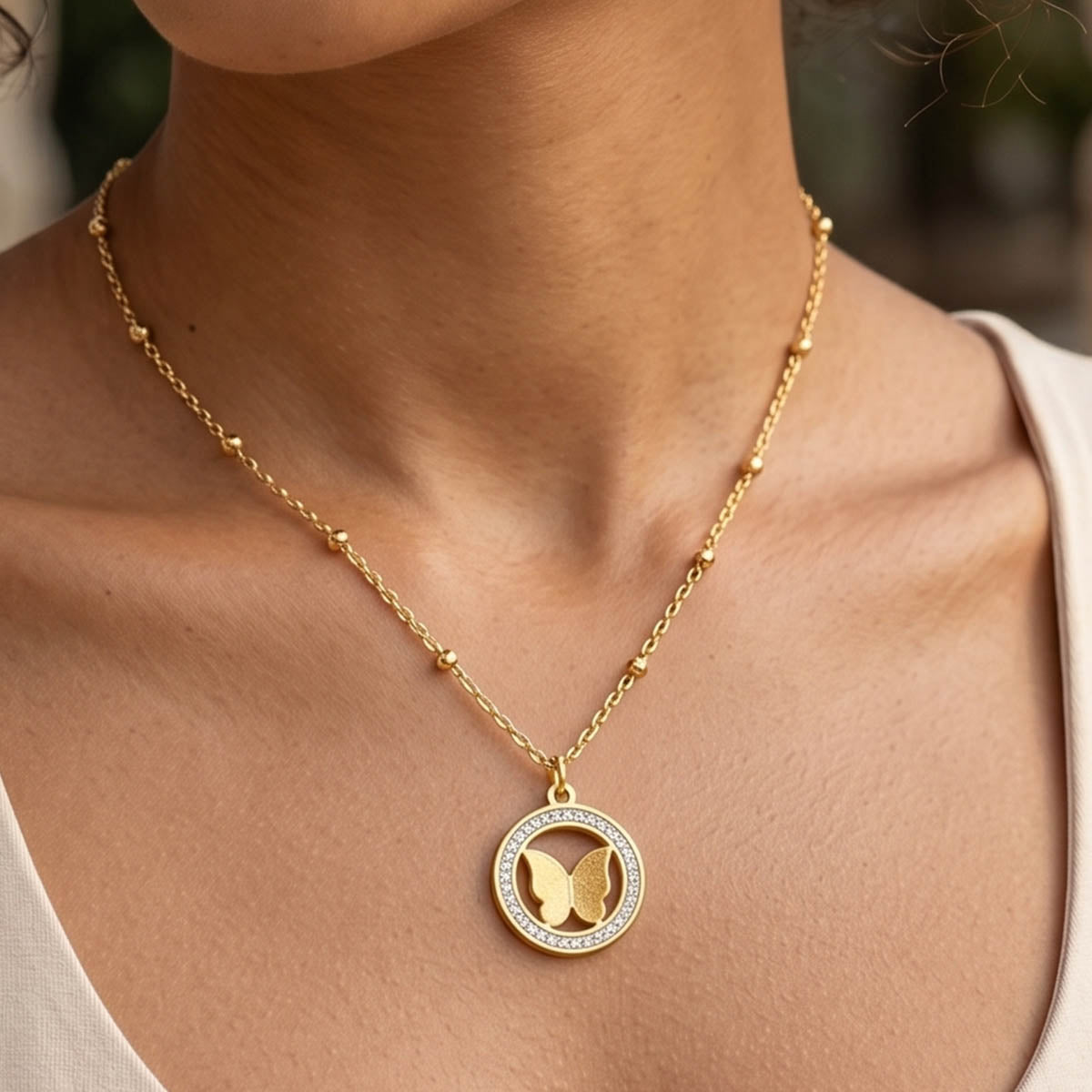 Goldene Edelstahl Halskette mit Schmetterling Anhänger am Hals eines Models getragen.