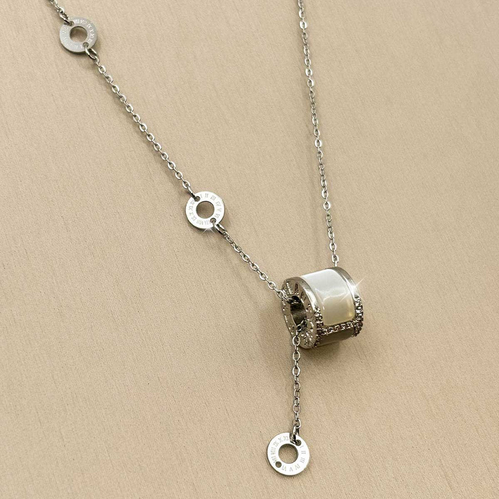 Silberfarbene Damen-Halskette aus Edelstahl im Y-Design mit kleinen Logoringen und einem zylindrischen Anhänger mit hellem Inlay, Nahaufnahme.