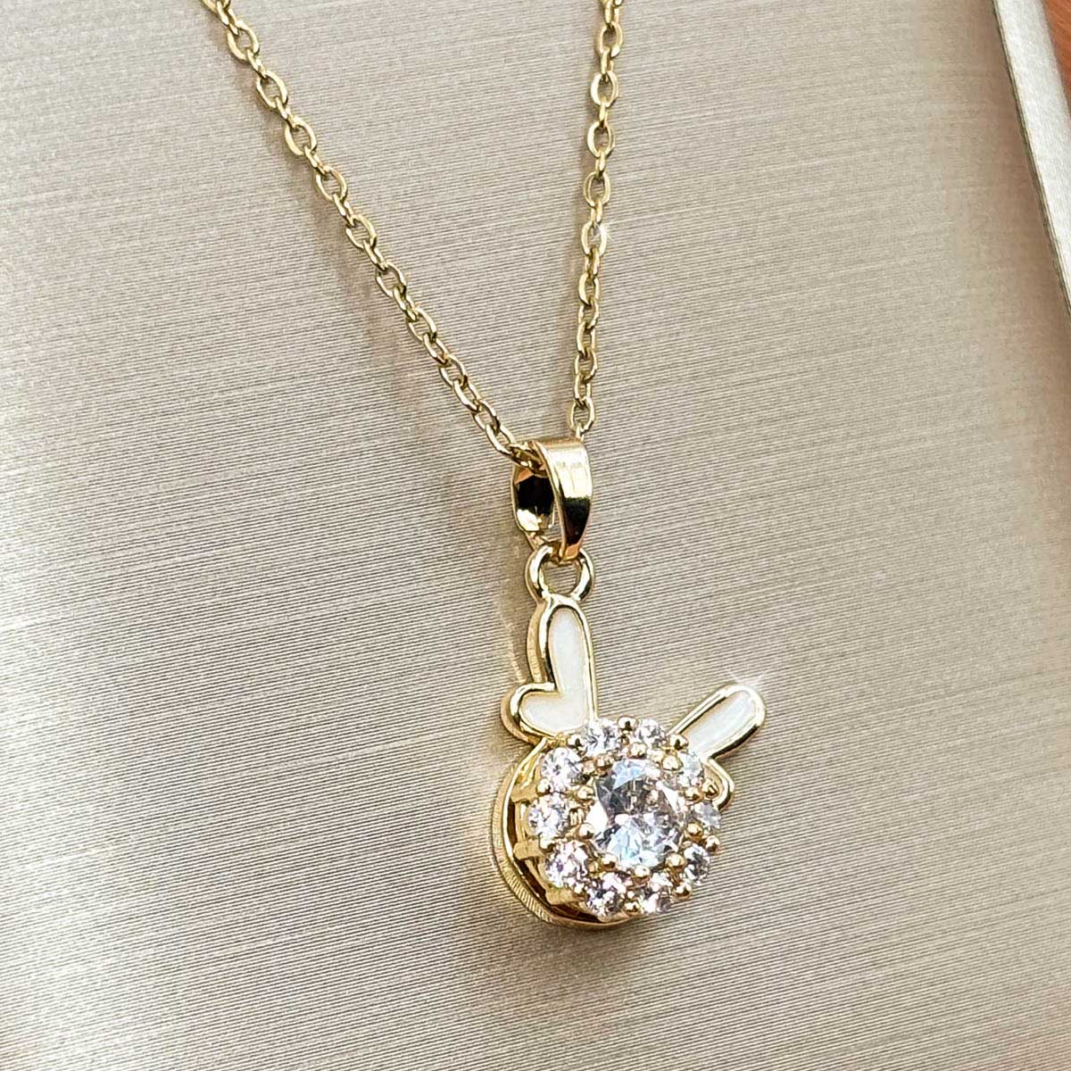Goldfarbene Edelstahl-Halskette für Damen mit einem runden Solitär-Zirkonia-Anhänger und minimalistischen Hasenohren-Details, Studioaufnahme.