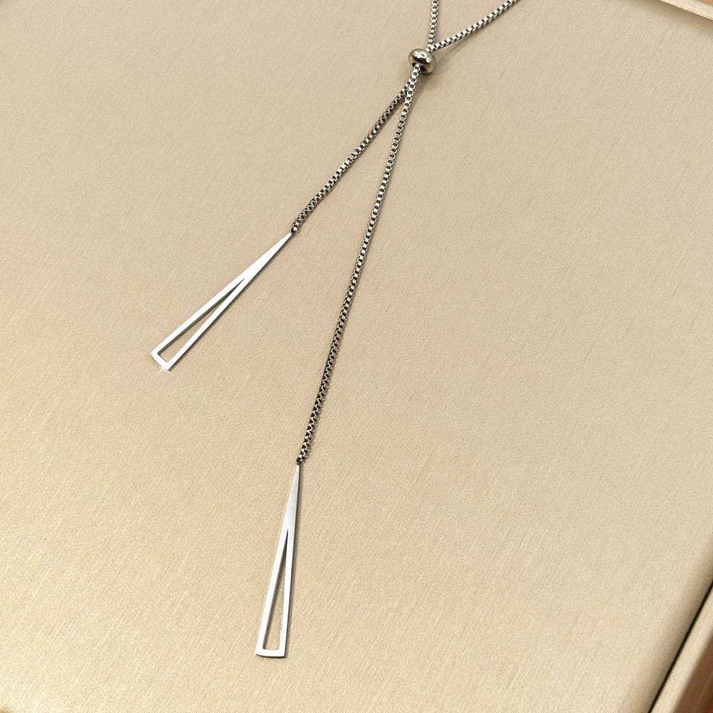 Silberfarbene Damen-Halskette aus Edelstahl im minimalistischen Y-Design mit verstellbarer Perle und zwei hängenden, geometrischen Dreiecks-Elementen, Nahaufnahme.