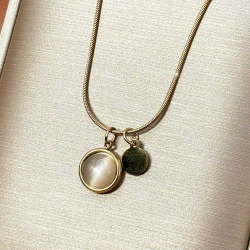 Silberfarbene Damen-Halskette aus Edelstahl an feiner Schlangenkette mit einer runden, zart schimmernden Plakette und einem kleinen Metall-Plättchen, Produktfoto