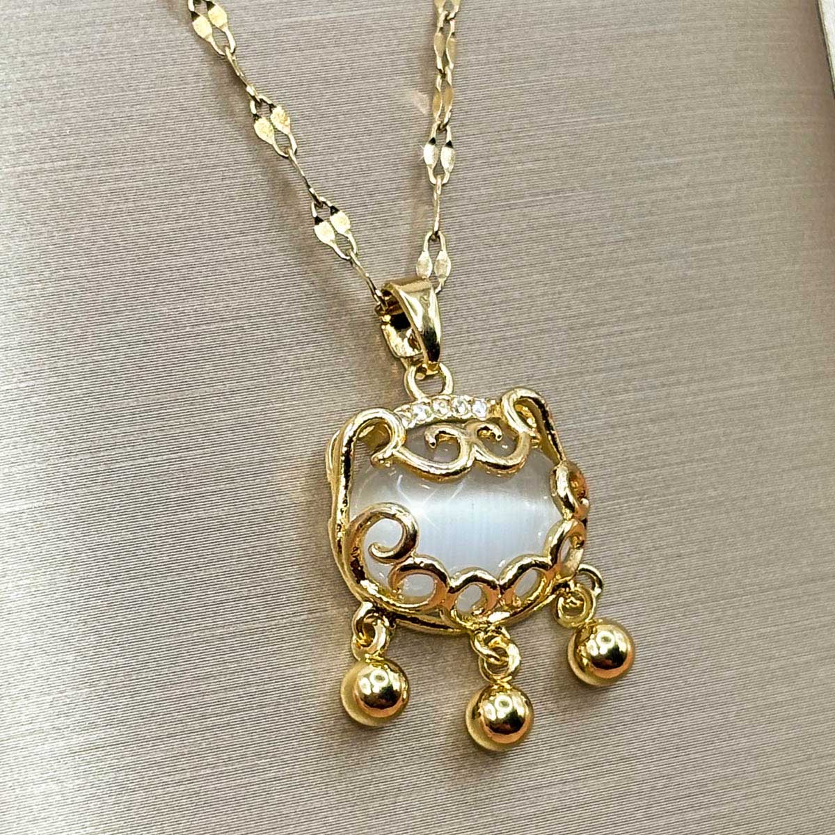 Goldfarbene Edelstahl-Halskette für Damen mit einer verzierten Plakette im asiatischen Schloss-Design und kleinen Hänge-Charms, Produktfoto.