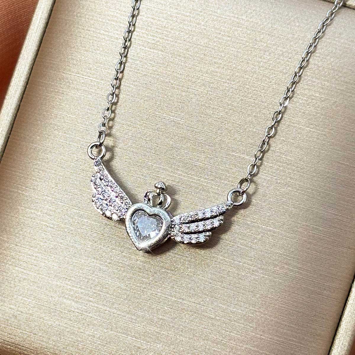 Silberfarbene Edelstahl-Halskette für Damen im Collier-Stil mit einem zentralen Herz-Zirkonia, umrahmt von weit ausgestreckten Engelsflügeln, Produktfoto