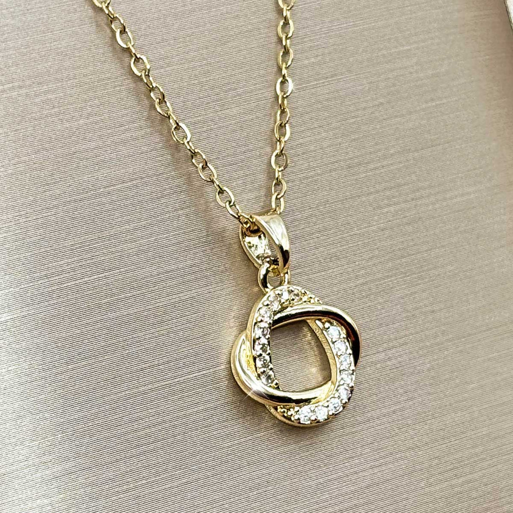 Goldfarbene Damen-Halskette aus Edelstahl mit einem abstrakten, ringförmig verschlungenen Anhänger, der dezent mit Zirkonia verziert ist, Produktfoto.