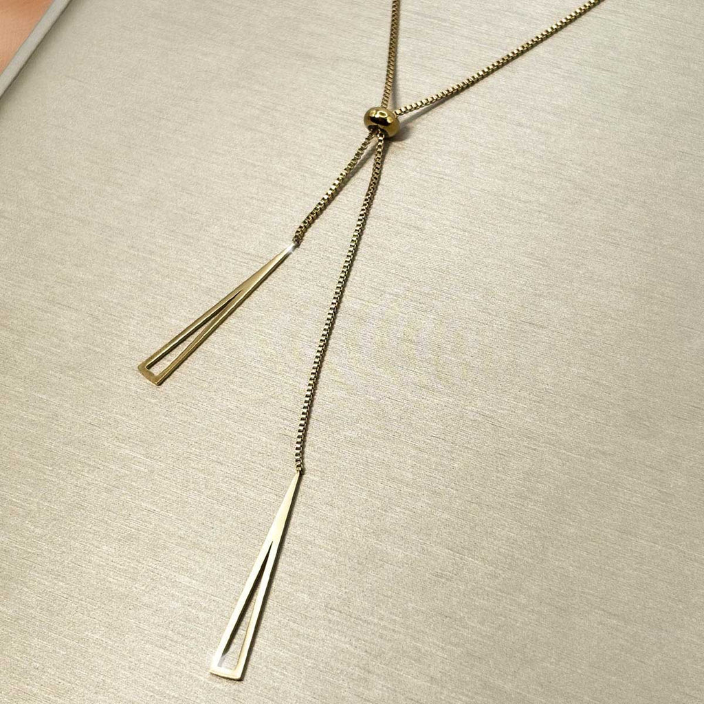 Goldfarbene Damen-Halskette aus Edelstahl im minimalistischen Y-Design mit verstellbarer Perle und zwei hängenden, geometrischen Dreiecks-Elementen, Nahaufnahme.