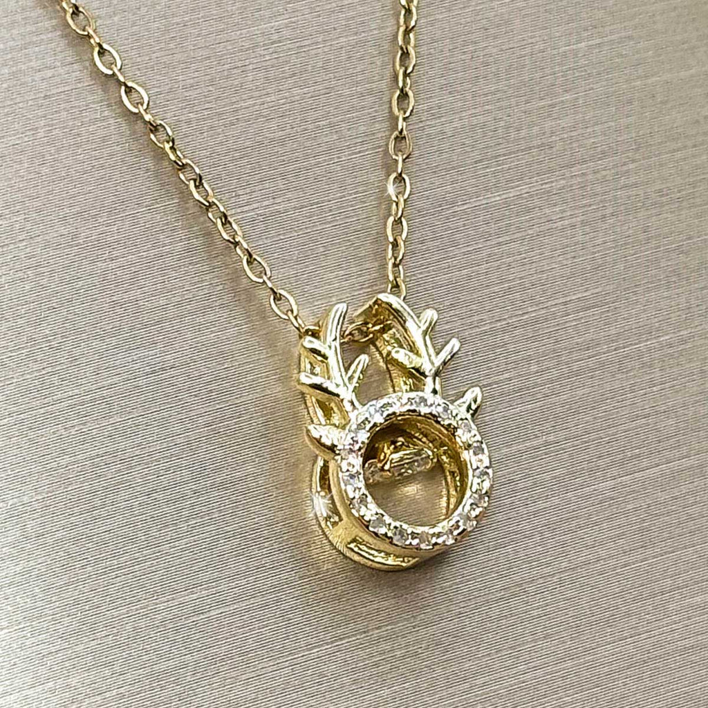 Goldfarbene Edelstahl-Halskette für Damen mit einem Hirschgeweih-Anhänger und beweglich gefasstem, tanzendem Zirkonia-Stein im Zentrum, Produktbild.