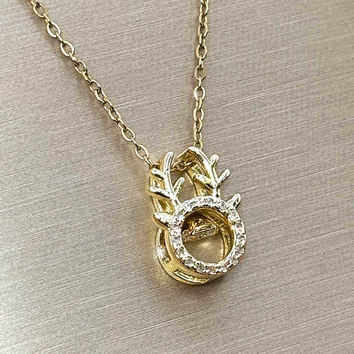 Goldfarbene Edelstahl-Halskette für Damen mit einem Hirschgeweih-Anhänger und beweglich gefasstem, tanzendem Zirkonia-Stein im Zentrum, Produktbild.