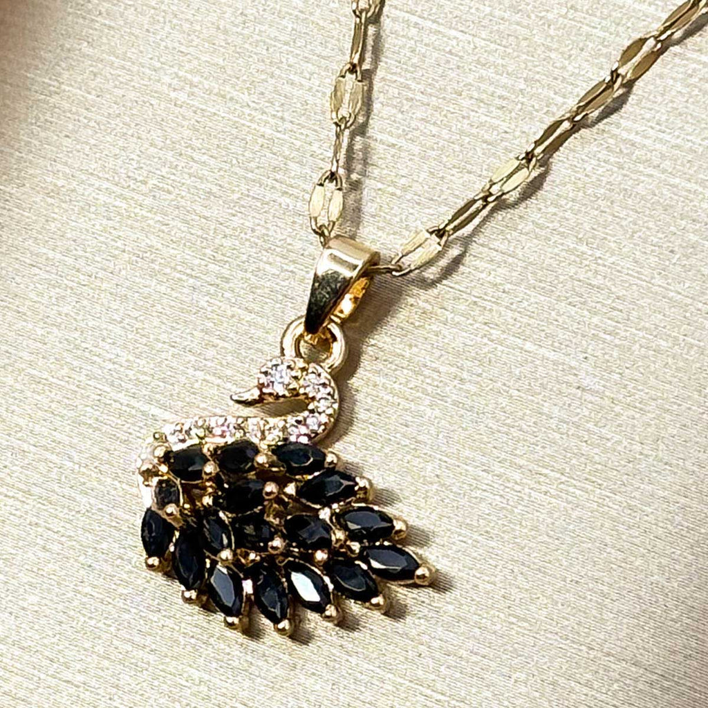 Goldfarbene Edelstahl-Halskette für Damen mit einem detailreichen Schwan-Anhänger, elegant besetzt mit tiefschwarzen Zirkonia-Steinen, Detail-Aufnahme.