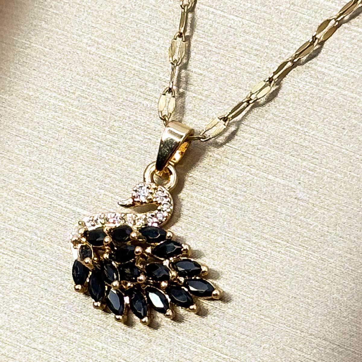 Goldfarbene Edelstahl-Halskette für Damen mit einem detailreichen Schwan-Anhänger, elegant besetzt mit tiefschwarzen Zirkonia-Steinen, Detail-Aufnahme.