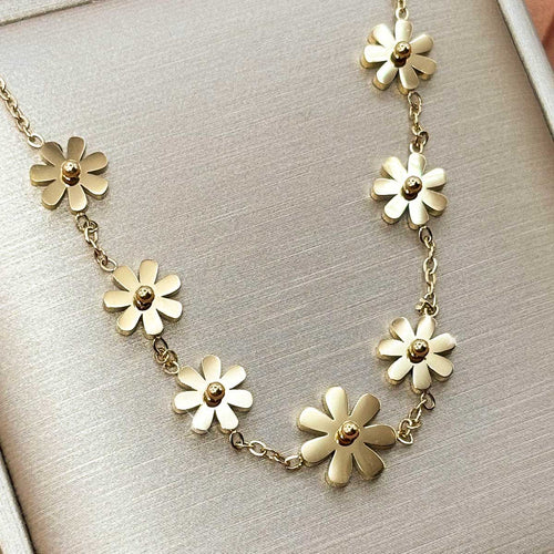 Goldfarbene Damen-Halskette aus Edelstahl, verziert mit einer Reihe fest integrierter, minimalistischer Blüten-Elemente, Vorderansicht.