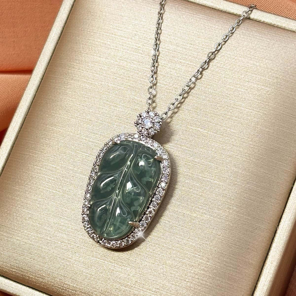 Silberfarbene Kette mit ovalem, grünem Blatt-Anhänger und glitzerndem Zirkonia-Rahmen, Produktfoto von links.