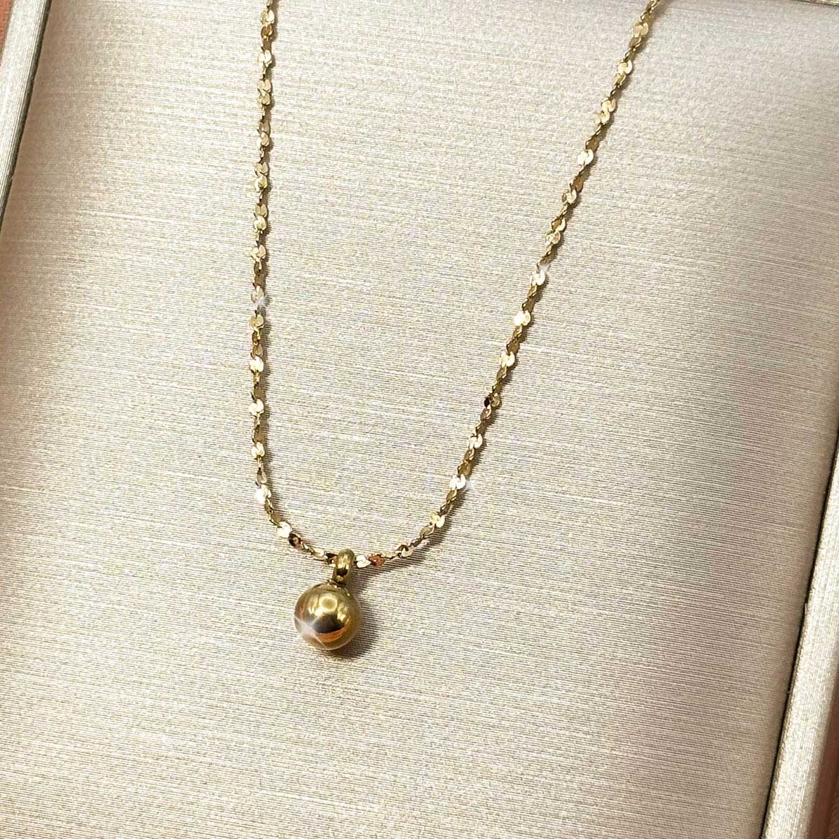 Goldfarbene Damen-Halskette aus Edelstahl mit einer schlichten, glänzenden Metallkugel an einer feinen Kette, Produktfoto