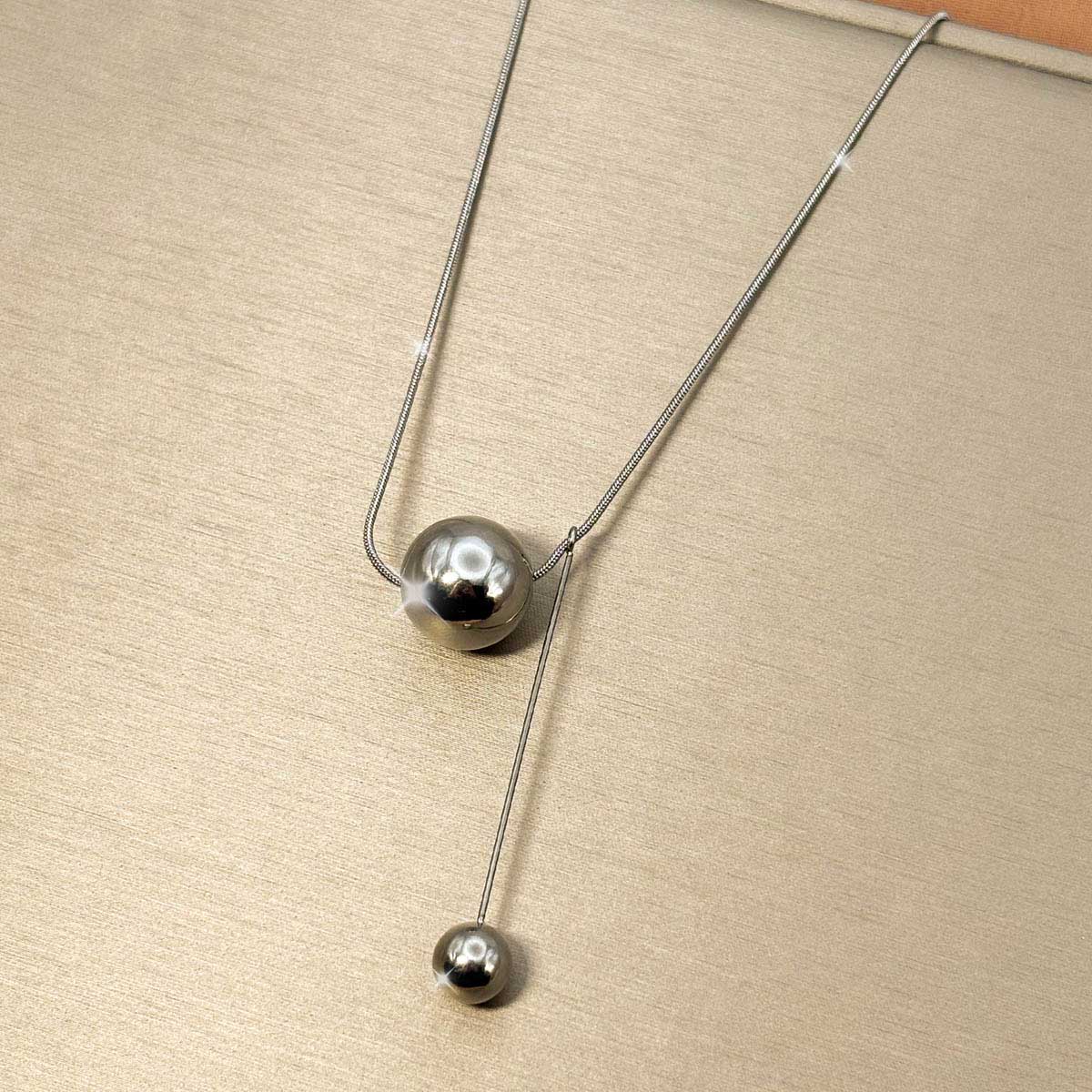 Silberfarbene Damen-Halskette aus Edelstahl im Y-Design mit zwei glänzenden, unterschiedlich großen Metallkugeln, Vorderansicht.