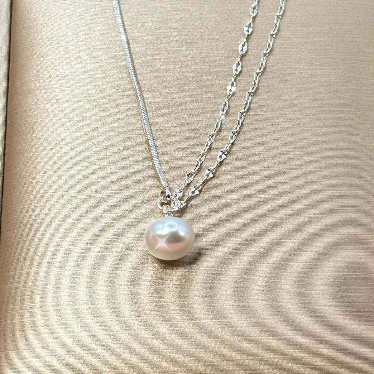 Zweireihige silberfarbene Halskette im Layering-Look mit einer hängenden, weißen Perle, Detail-Aufnahme Vorderansicht