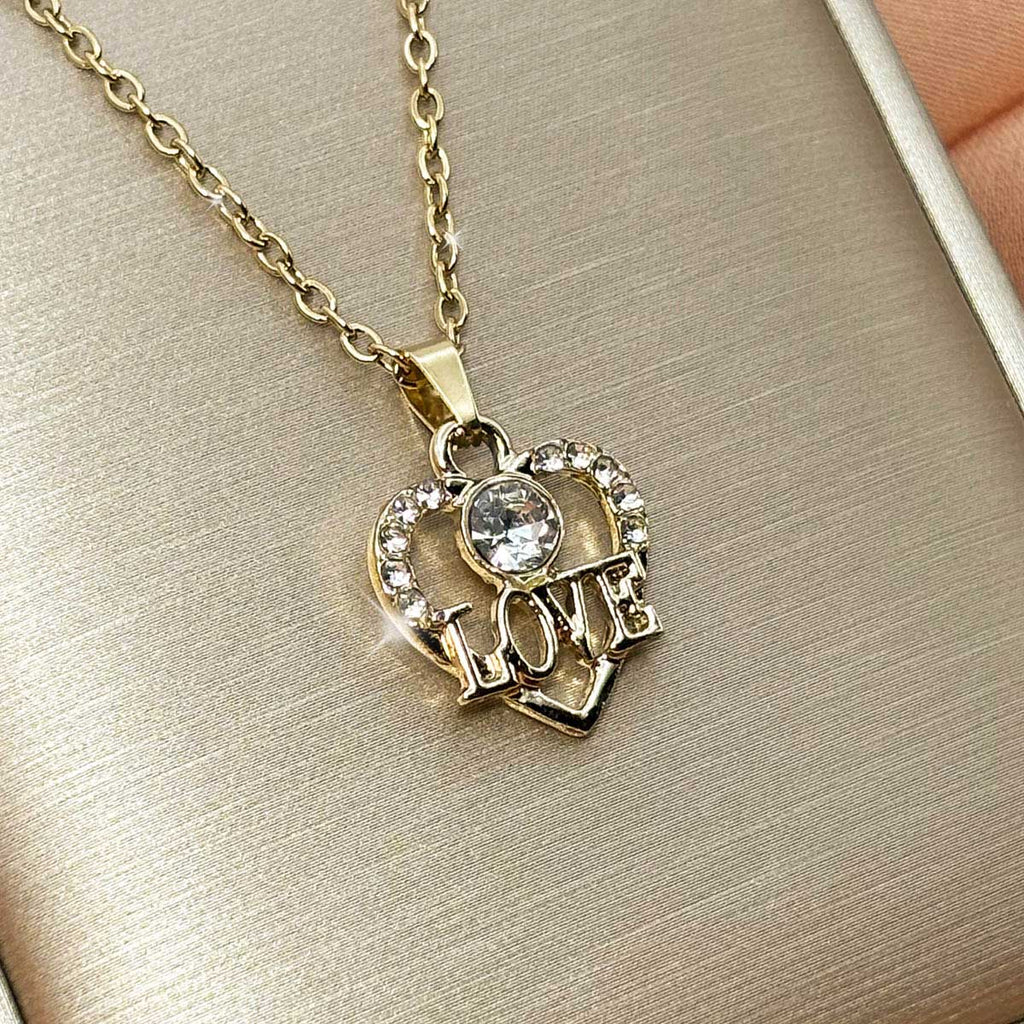 Goldfarbene Edelstahl-Halskette für Damen mit einem herzförmigen Anhänger, verziert mit Zirkonia-Steinen und LOVE-Schriftzug, Studioaufnahme.