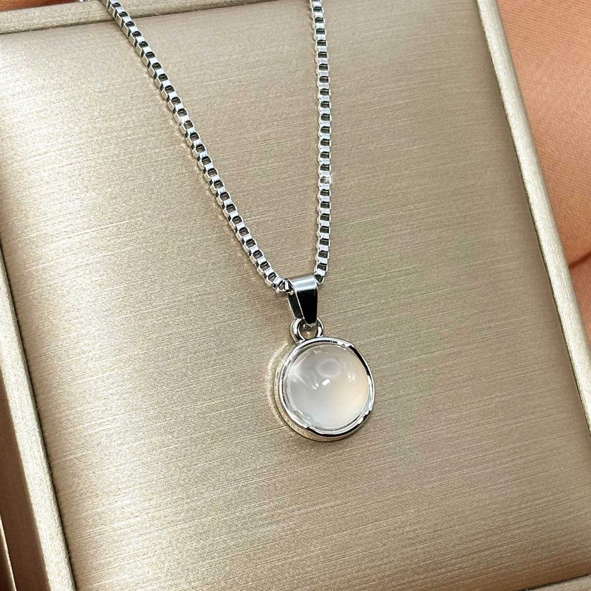 Silberfarbene Damen-Halskette aus Edelstahl mit einem runden, zart schimmernden Anhänger in Opal-Optik, Produtkfoto