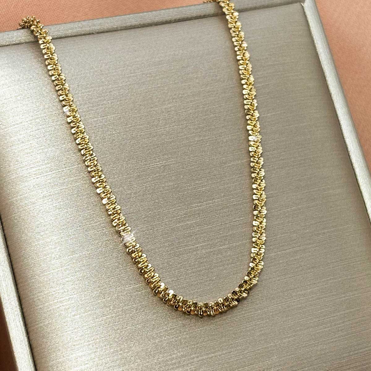Goldfarbene Damen-Halskette aus Edelstahl mit einer intensiv strukturierten, glitzernden Ketten-Struktur, Freisteller.
