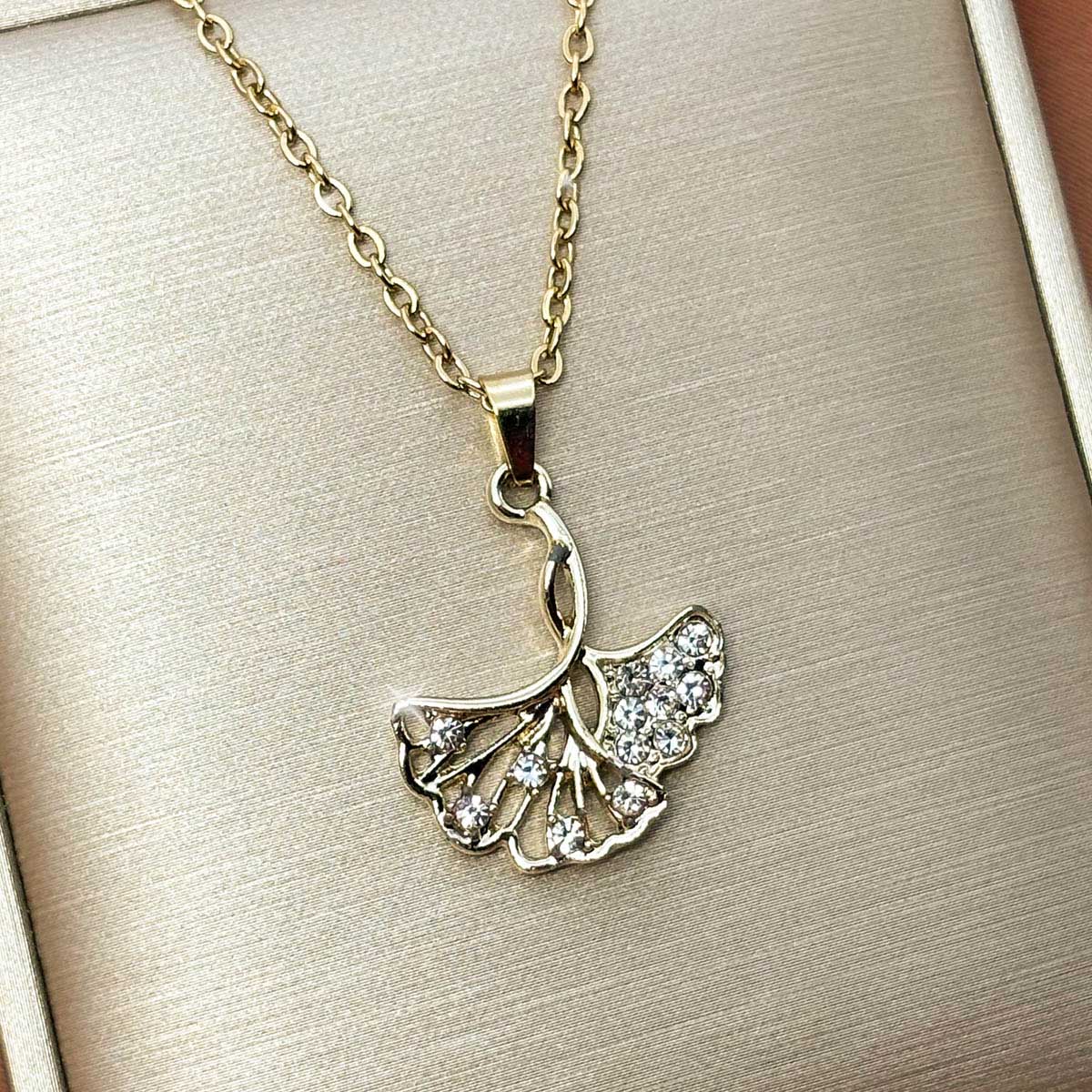 Goldfarbene Damen-Halskette aus Edelstahl mit einem elegant gefächerten Ginkgoblatt-Anhänger und feinem Zirkonia-Besatz, Produktfoto.