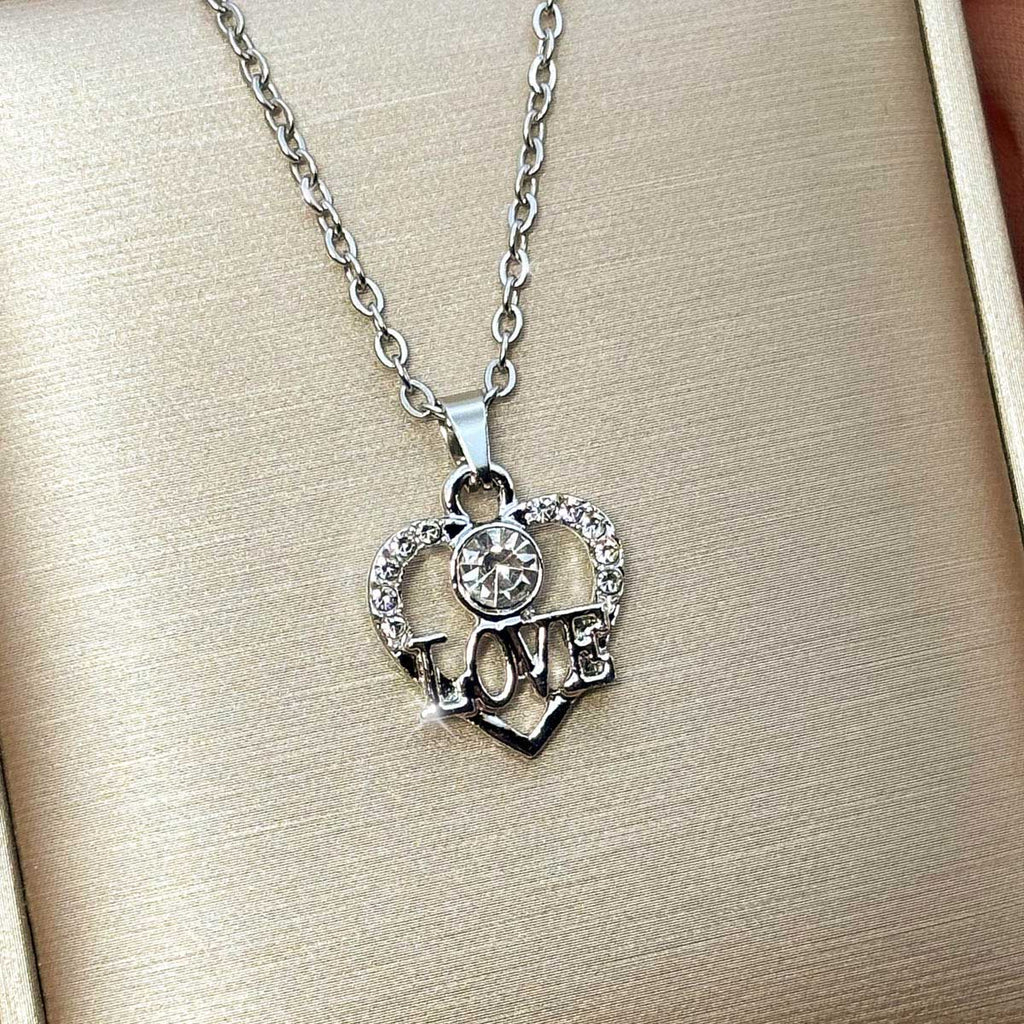 Silberfarbene Damen-Halskette aus Edelstahl mit einem herzförmigen Anhänger, verziert mit Zirkonia-Steinen und LOVE-Schriftzug, Nahaufnahme.