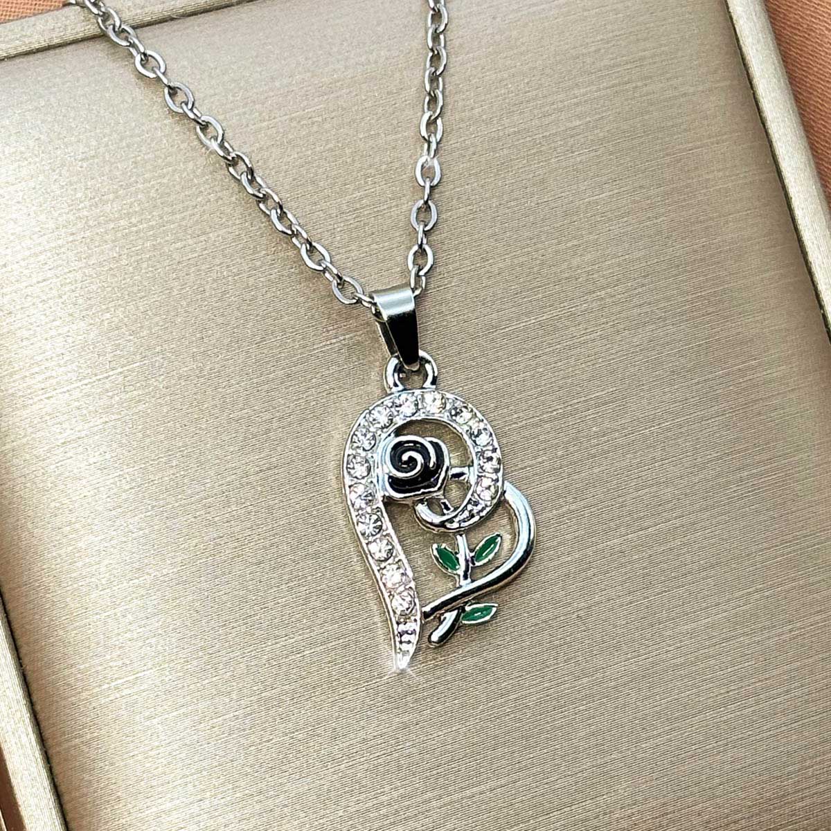 Silberfarbene Damen-Halskette aus Edelstahl mit einem geschwungenen Herz-Anhänger, verziert mit einer kleinen Rose und Zirkonia, Produktfoto.