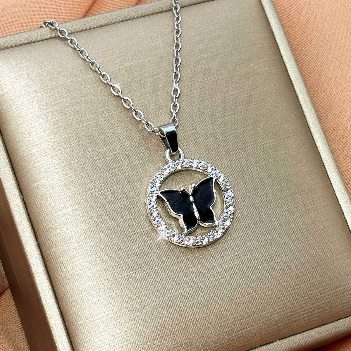 Silberfarbene Edelstahl-Halskette für Damen mit einer runden, zirkoniabesetzten Plakette und schwarzem Schmetterlings-Motiv, Produktfoto
