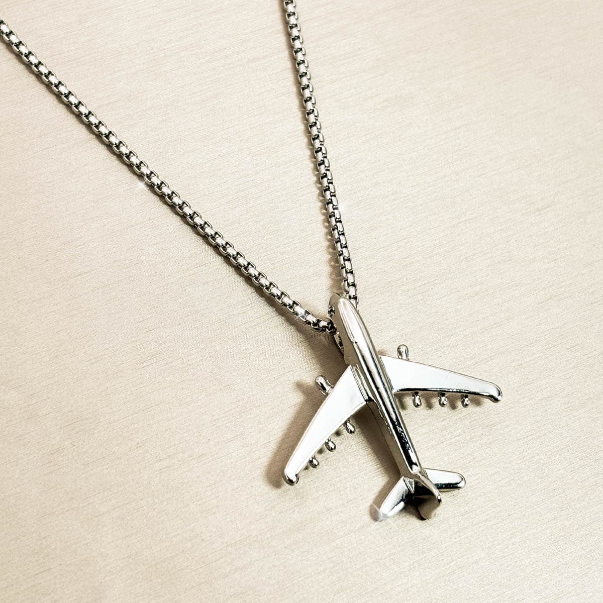 Herren-Halskette aus Edelstahl in Silber mit minimalistischem Flugzeug-Anhänger, Nahaufnahme von rechts.