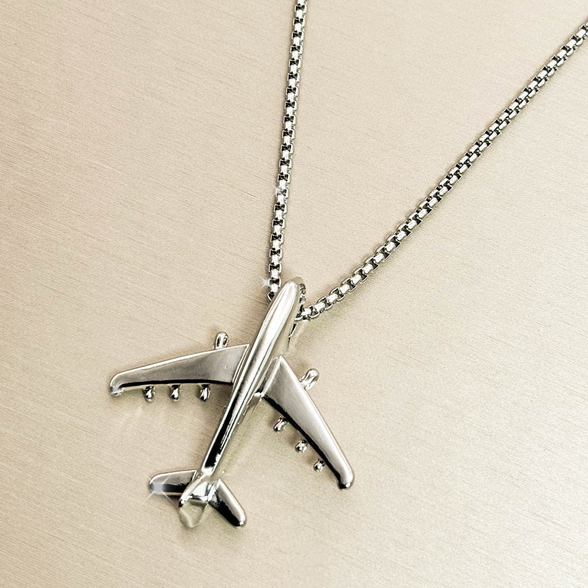 Herren-Halskette aus Edelstahl in Silber mit minimalistischem Flugzeug-Anhänger, Produktfoto von links