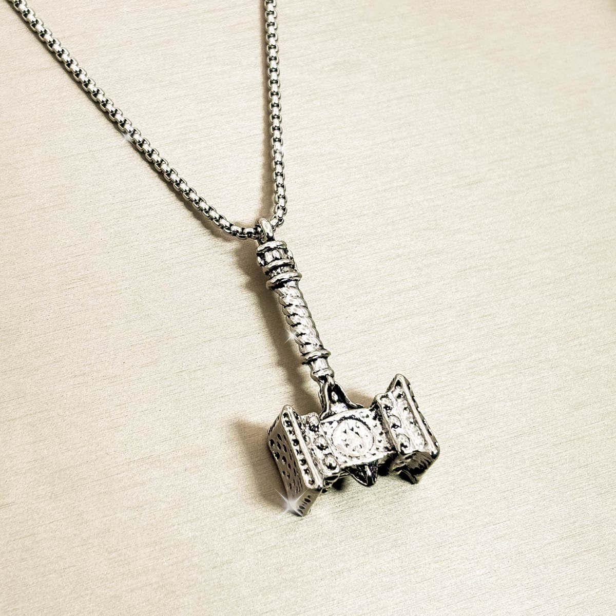 Silberfarbene Edelstahl-Herrenkette mit detailreichem Thors-Hammer-Anhänger, von links.
