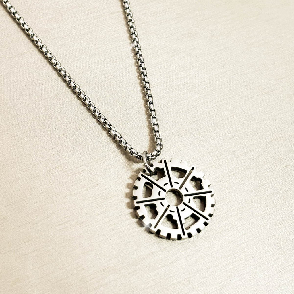 Herren-Halskette mit silberfarbenem Zahnrad-Anhänger im Industrial-Stil aus Edelstahl, Nahaufnahme von links.