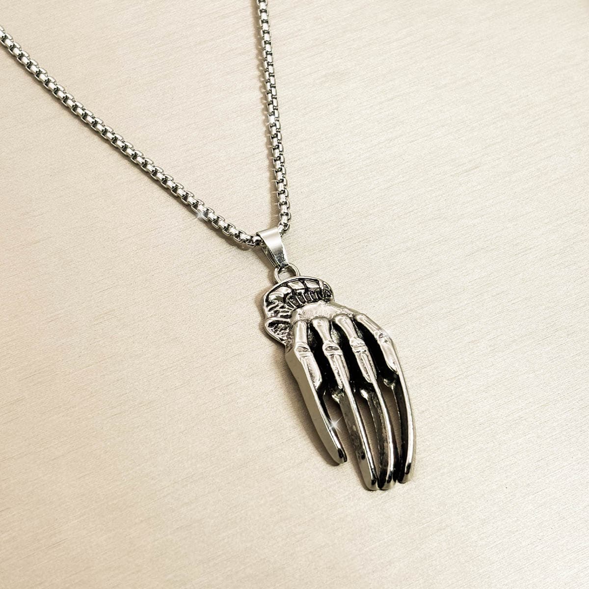 Silberfarbene Edelstahl-Herrenkette mit detailreichem Skeletthand-Anhänger, Produktfoto in Nahaufnahme