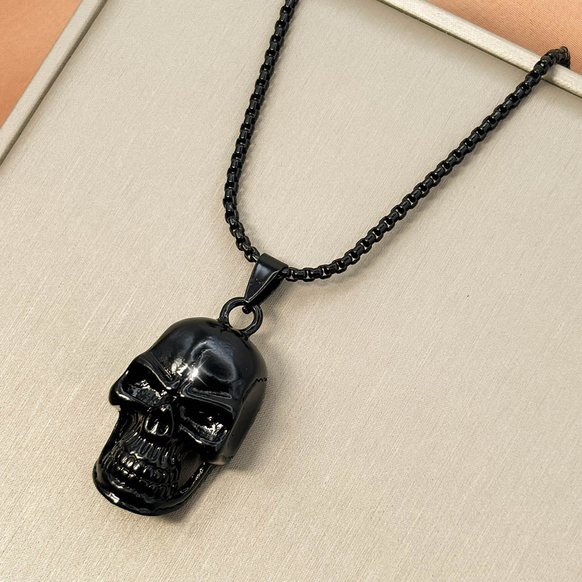 Schwarze Herren-Halskette aus Edelstahl an einer feinen Rundanker-Kette mit einem glänzenden Totenkopf-Anhänger, Produktfoto