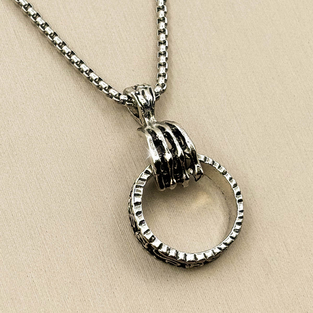 Silberfarbene Herren-Halskette aus Edelstahl mit einem strukturierten Ring-Anhänger, gehalten von einer steinernen Klaue, Vorderansicht.