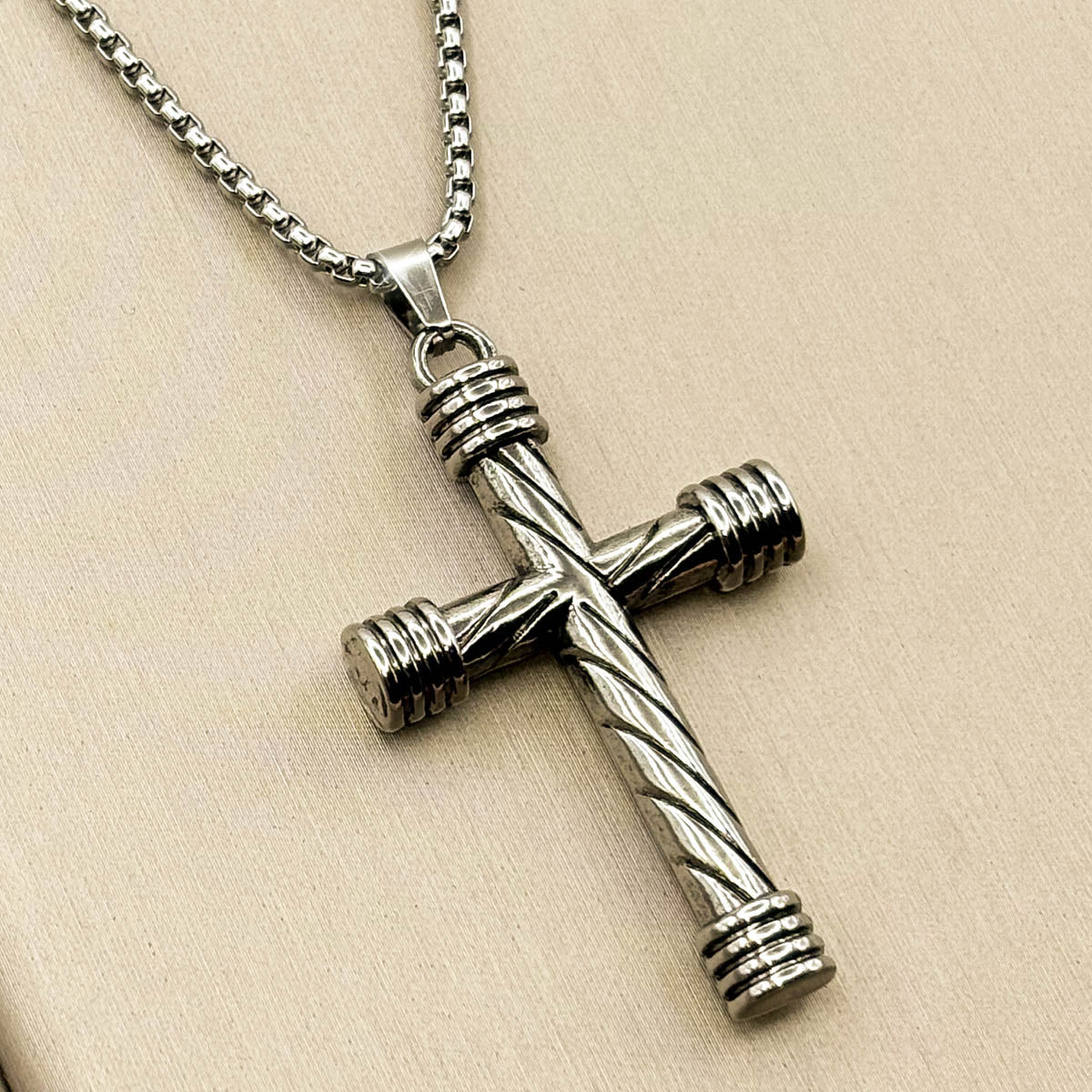 Silberfarbene Herren-Halskette aus Edelstahl mit einem modernen Kreuz-Anhänger aus strukturierten Rundstäben, Produktfoto.
