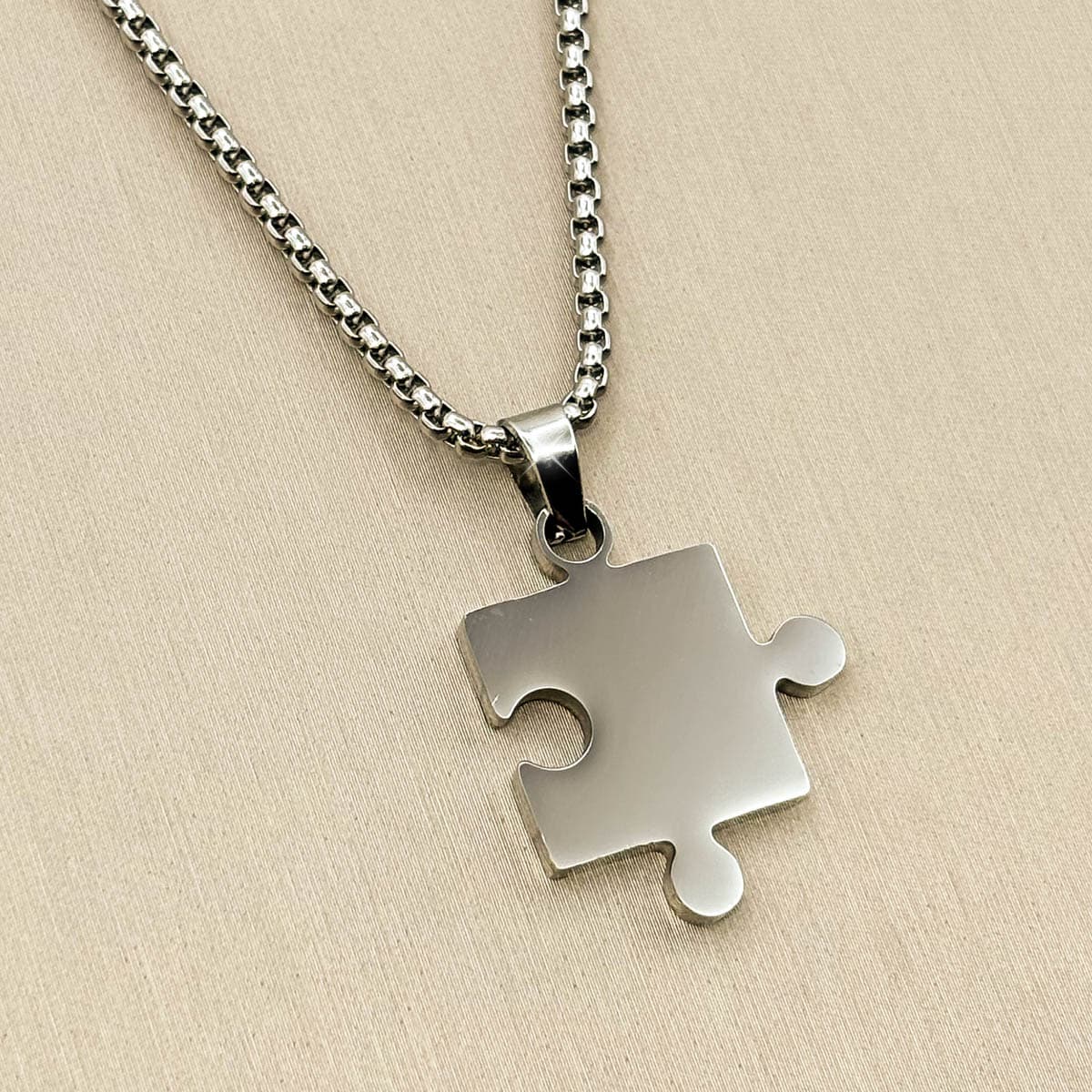 Herren-Kette aus Edelstahl in Silber mit einem minimalistischen, glatten Puzzleteil-Anhänger, Detail-Aufnahme von links