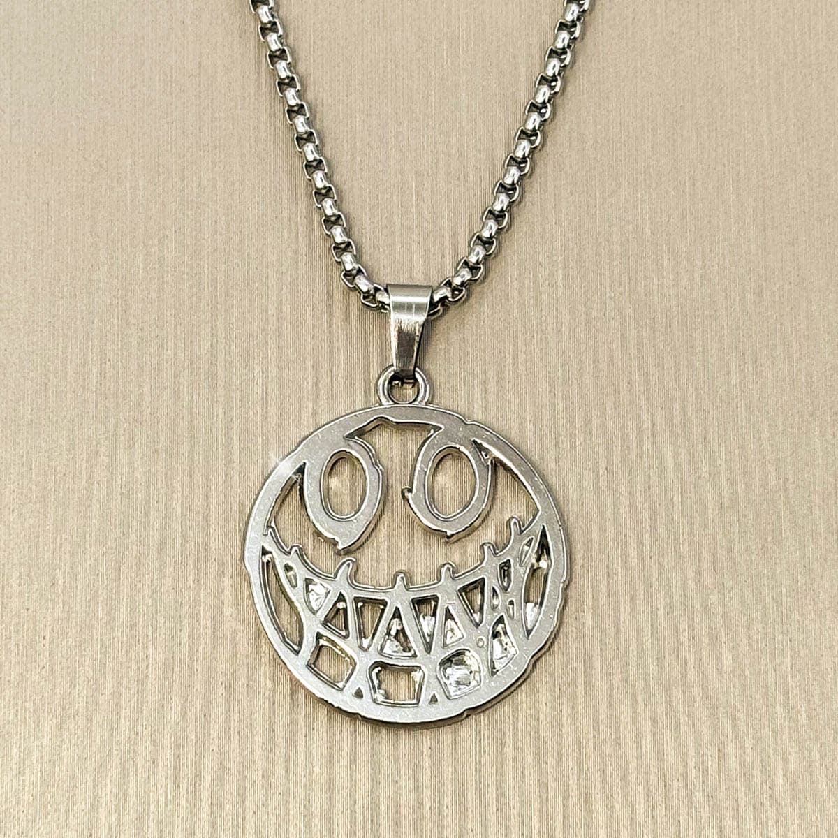 Herren-Halskette aus Edelstahl in Silber mit einem runden, grinsenden Smiley-Anhänger im Cut-Out-Design, Produktfoto.