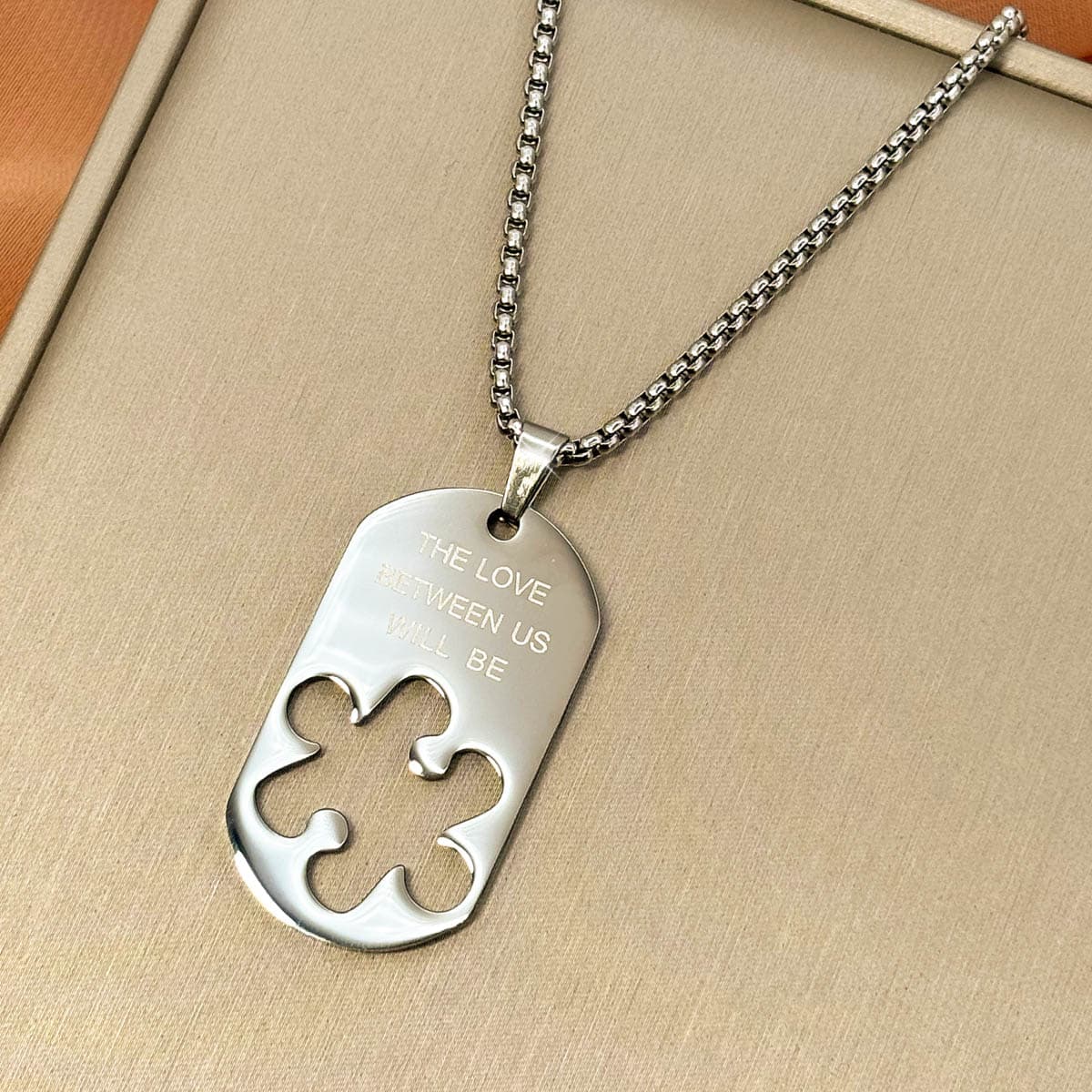 Herren-Halskette mit silberfarbenem Dog-Tag-Anhänger, Gravur und ausgestanzter Puzzleteil-Form aus Edelstahl, Nahaufnahme von rechts.
