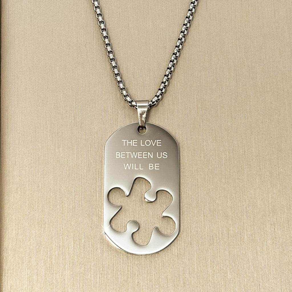 Herren-Halskette mit silberfarbenem Dog-Tag-Anhänger, Gravur und ausgestanzter Puzzleteil-Form aus Edelstahl, Nahaufnahme.